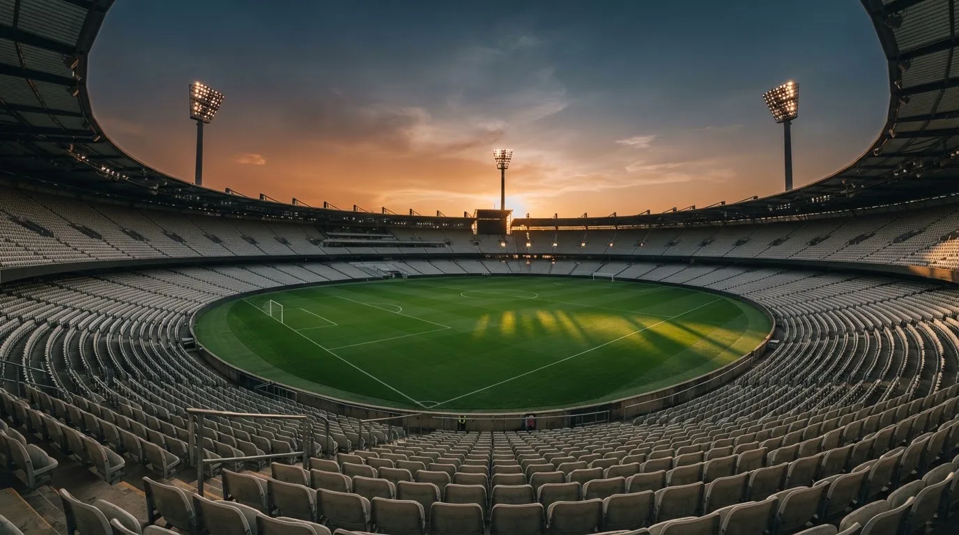 Un estadio de fútbol vacío con torres de iluminación al atardecer