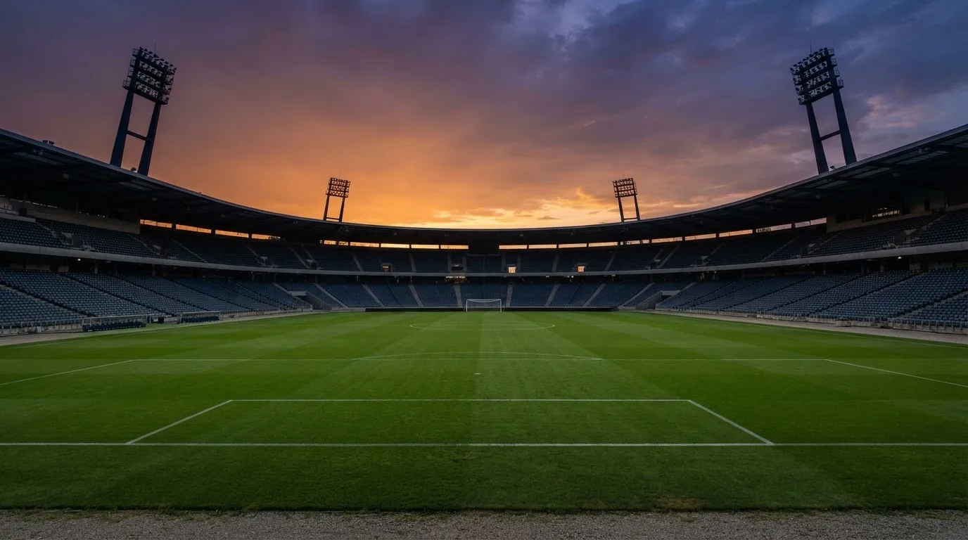 Un estadio de fútbol vacío con torres de iluminación al atardecer