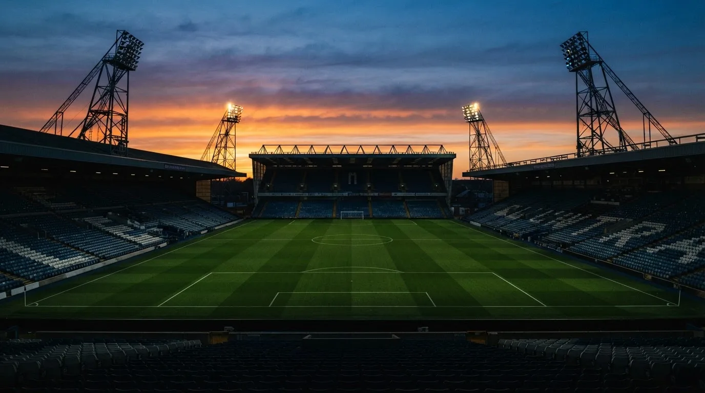 Un estadio de fútbol vacío con torres de iluminación al atardecer