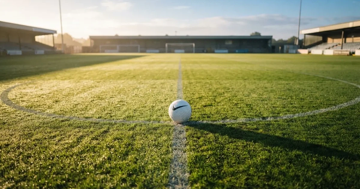 Un balón en el punto central de un campo de césped a la luz de la mañana