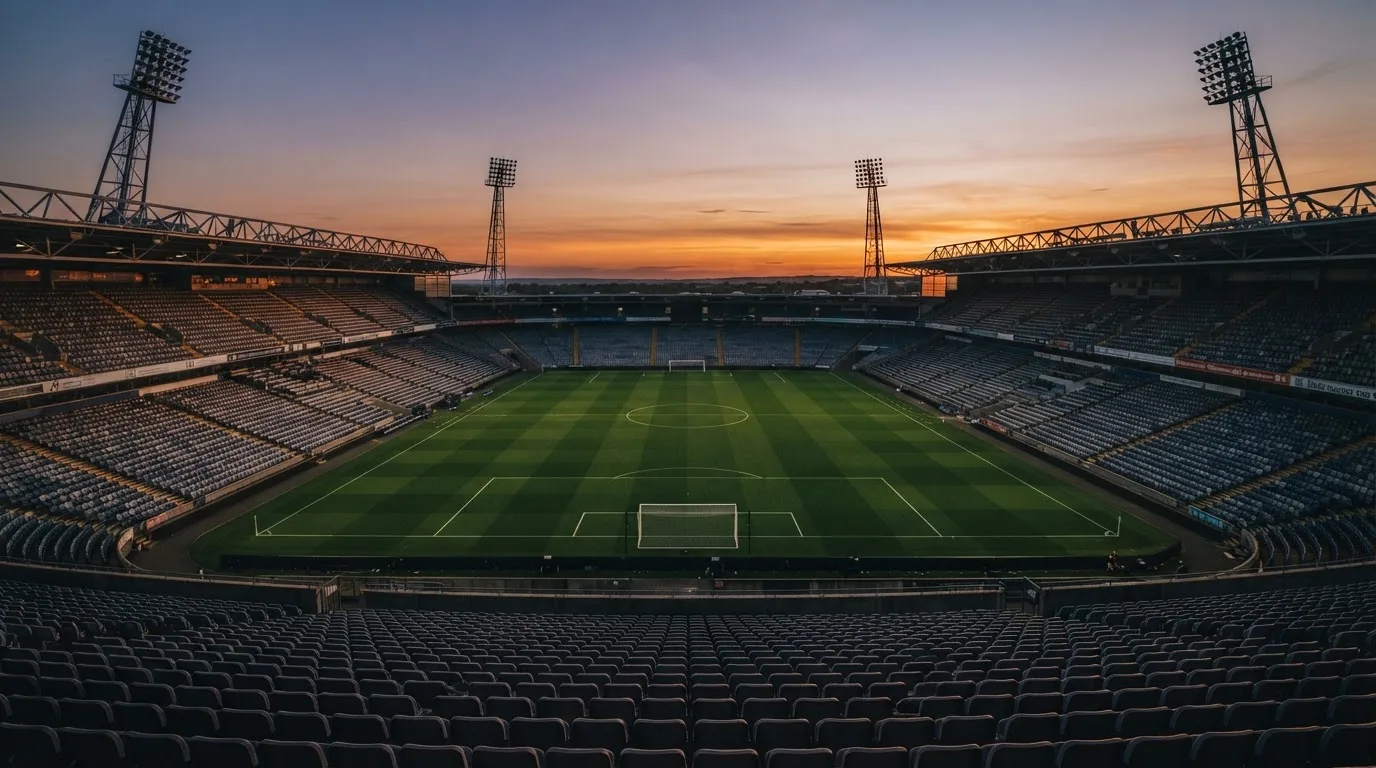 Un estadio de fútbol vacío con torres de iluminación al atardecer