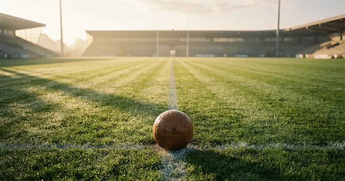 Un balón en el punto central de un campo de césped a la luz de la mañana