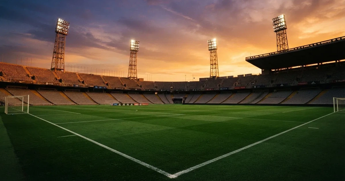 Un estadio de fútbol vacío con torres de iluminación al atardecer