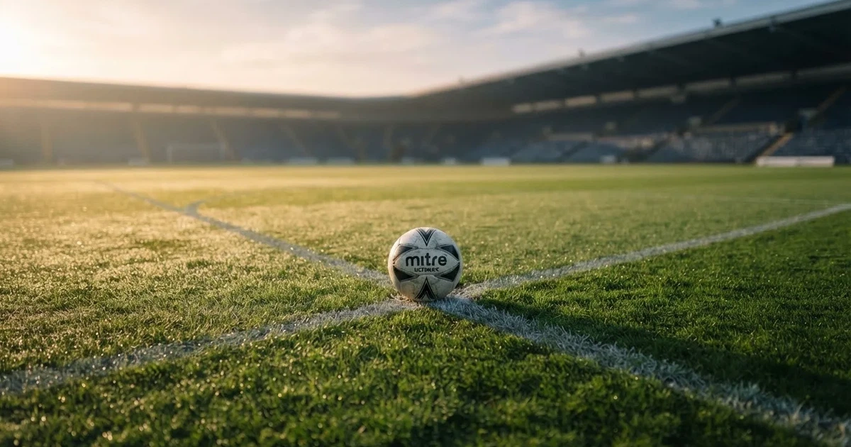 Un balón en el punto central de un campo de césped a la luz de la mañana