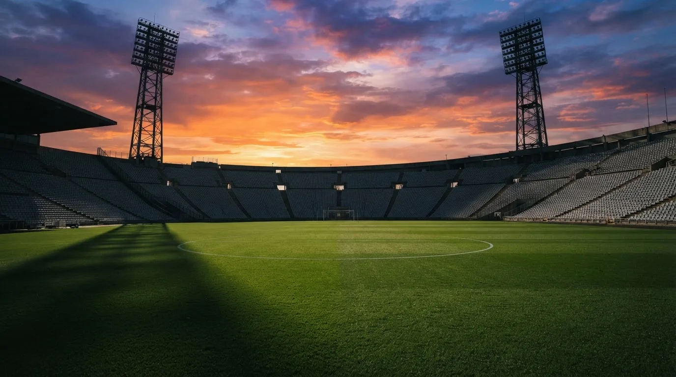 Un estadio de fútbol vacío con torres de iluminación al atardecer