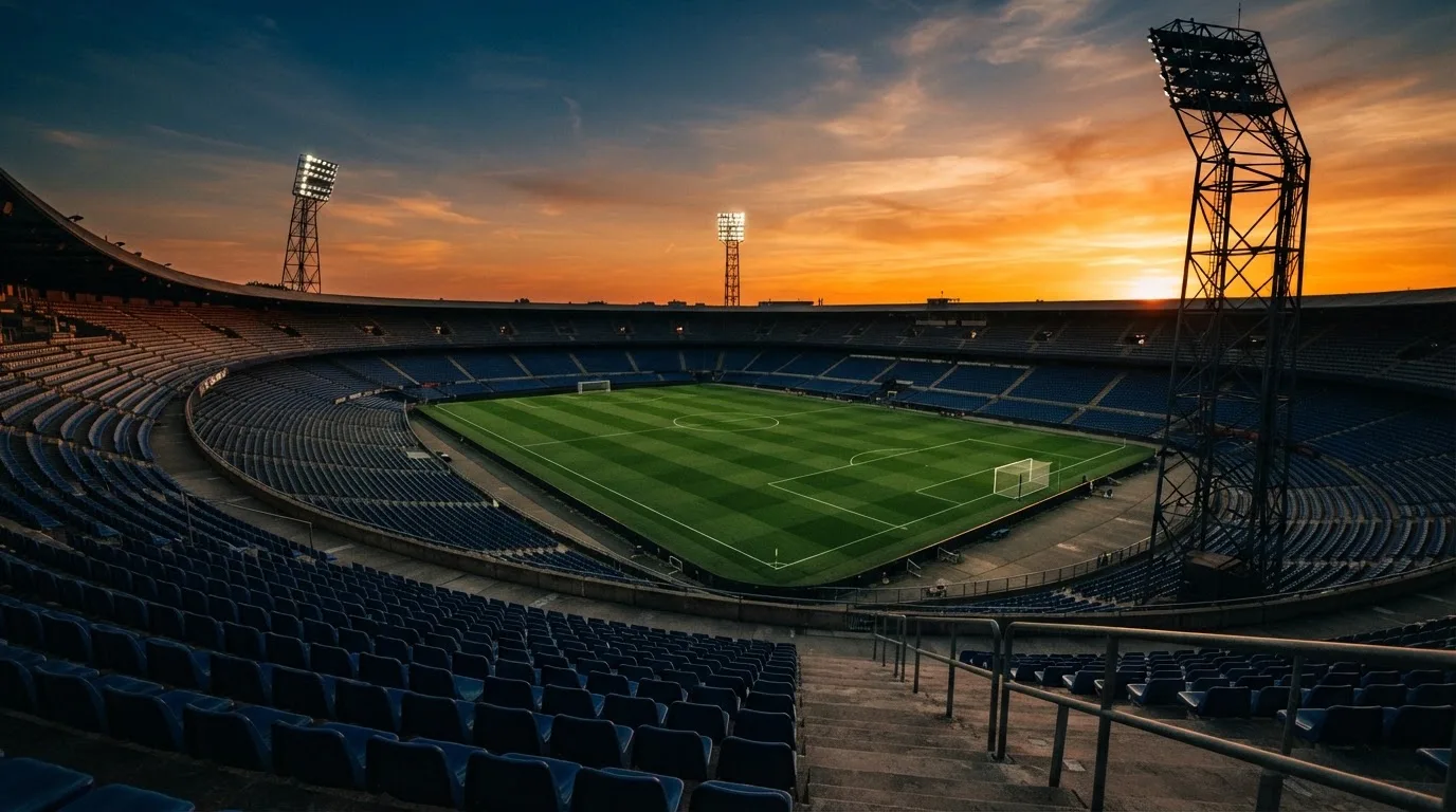 Un estadio de fútbol vacío con torres de iluminación al atardecer