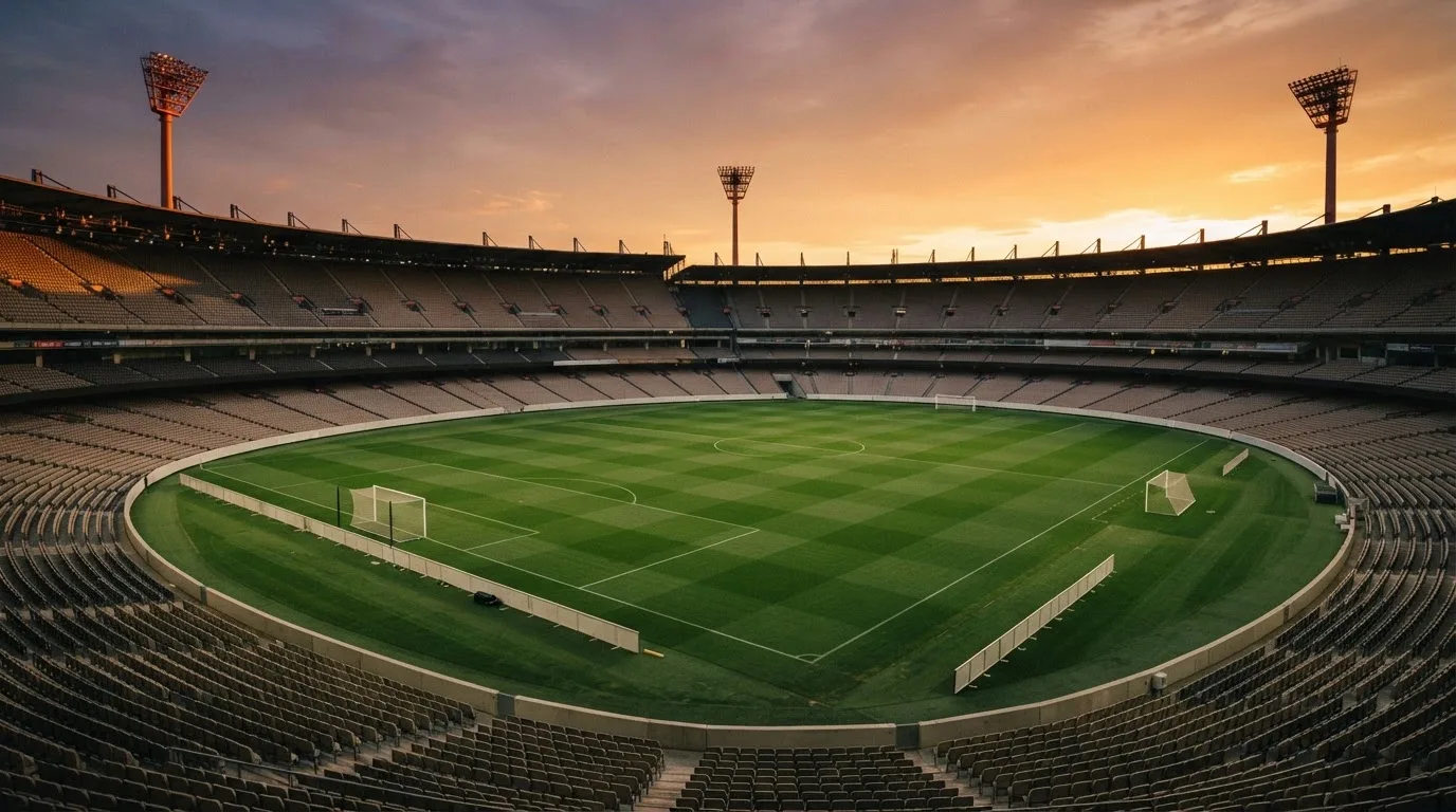 Un estadio de fútbol vacío con torres de iluminación al atardecer