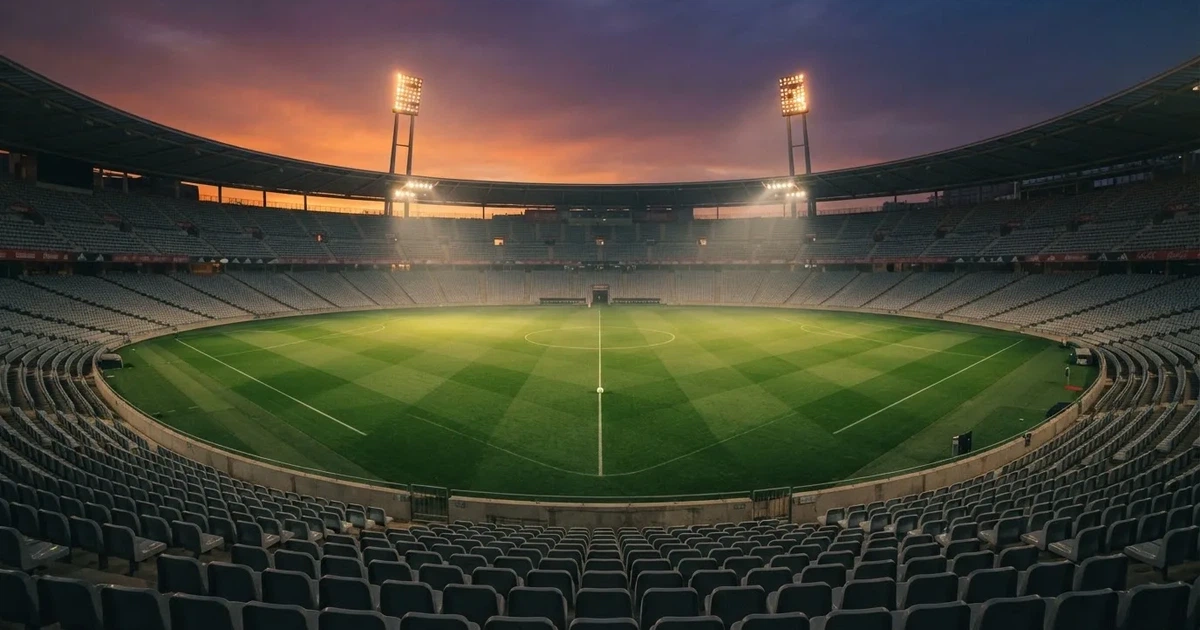 Un estadio de fútbol vacío con torres de iluminación al atardecer