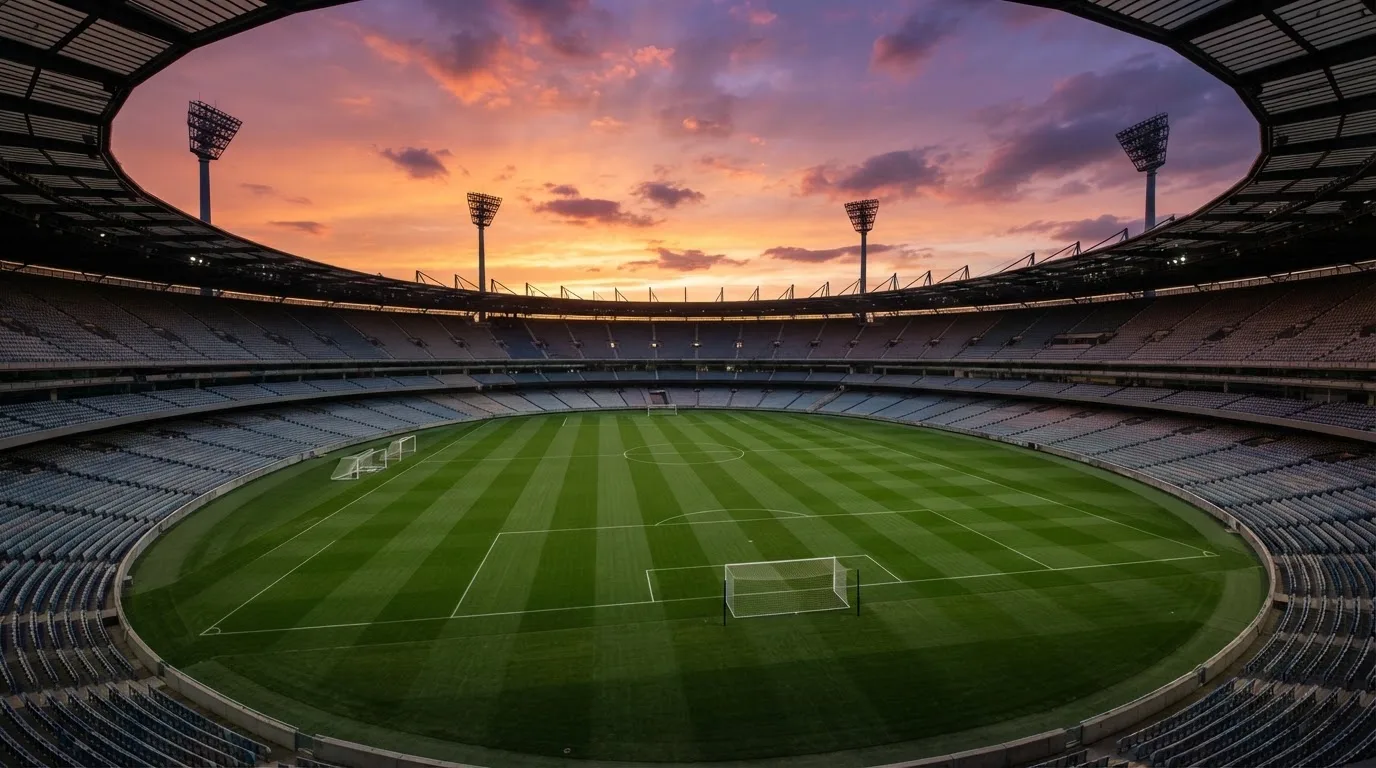 Un estadio de fútbol vacío con torres de iluminación al atardecer