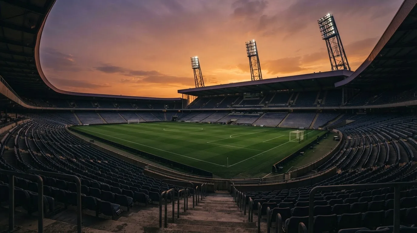 Un estadio de fútbol vacío con torres de iluminación al atardecer