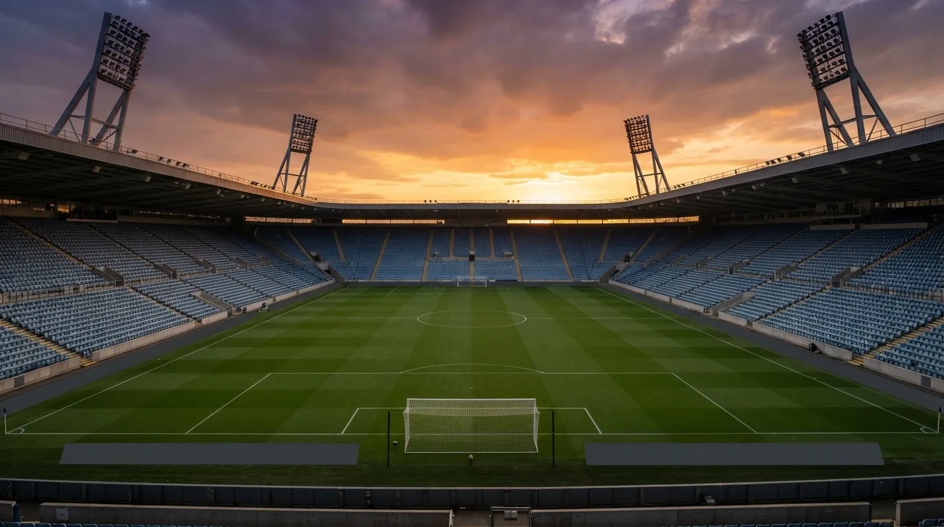 Un estadio de fútbol vacío con torres de iluminación al atardecer