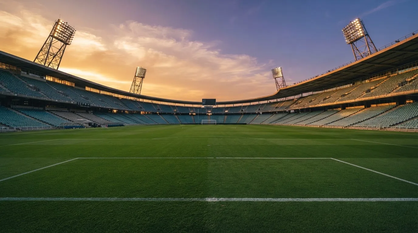 Un estadio de fútbol vacío con torres de iluminación al atardecer