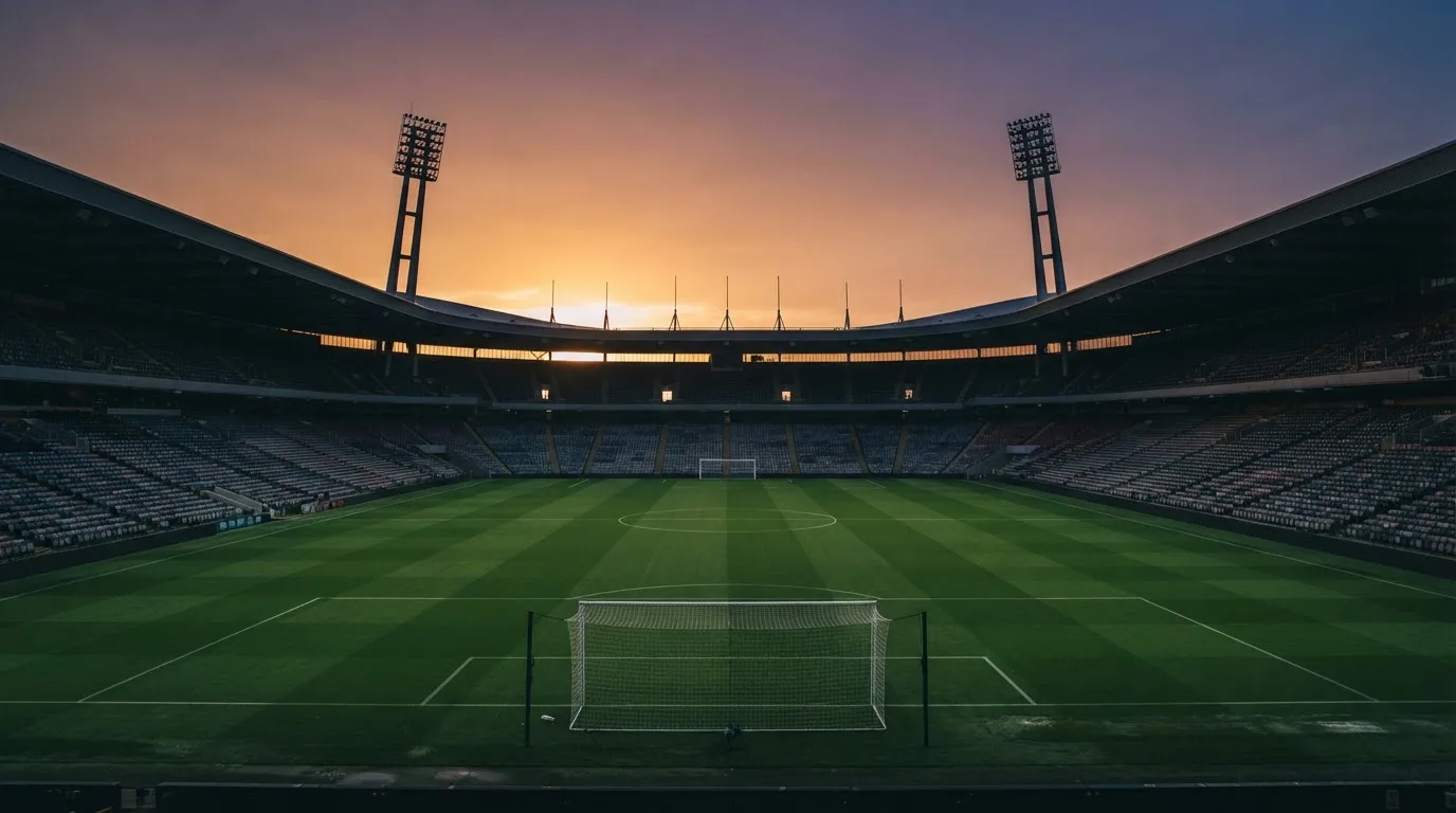 Un estadio de fútbol vacío con torres de iluminación al atardecer