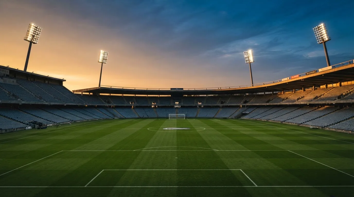 Un estadio de fútbol vacío con torres de iluminación al atardecer