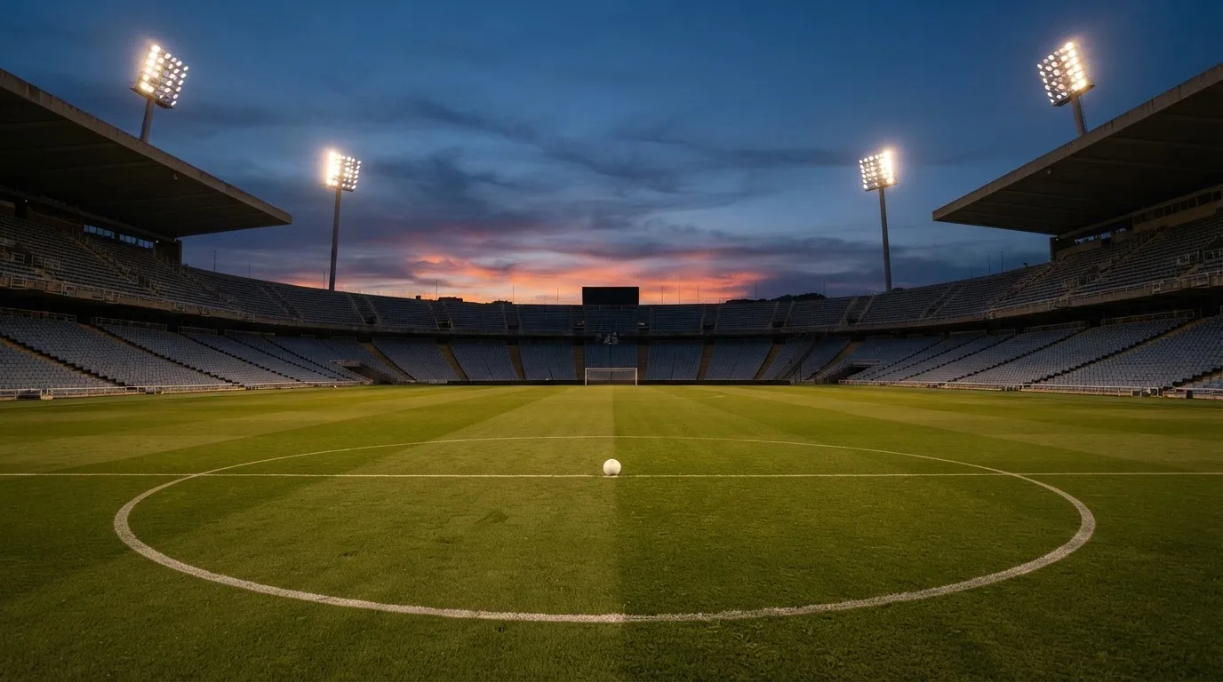 Un estadio de fútbol vacío con torres de iluminación al atardecer