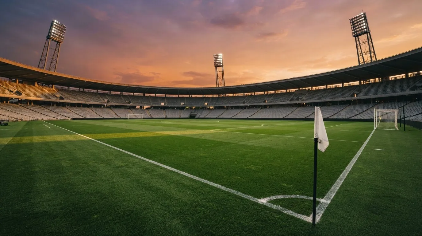 Un estadio de fútbol vacío con torres de iluminación al atardecer