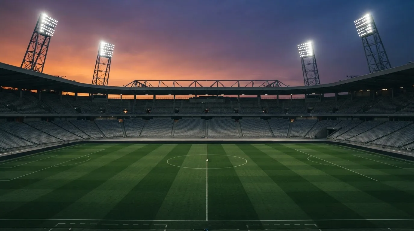 Un estadio de fútbol vacío con torres de iluminación al atardecer