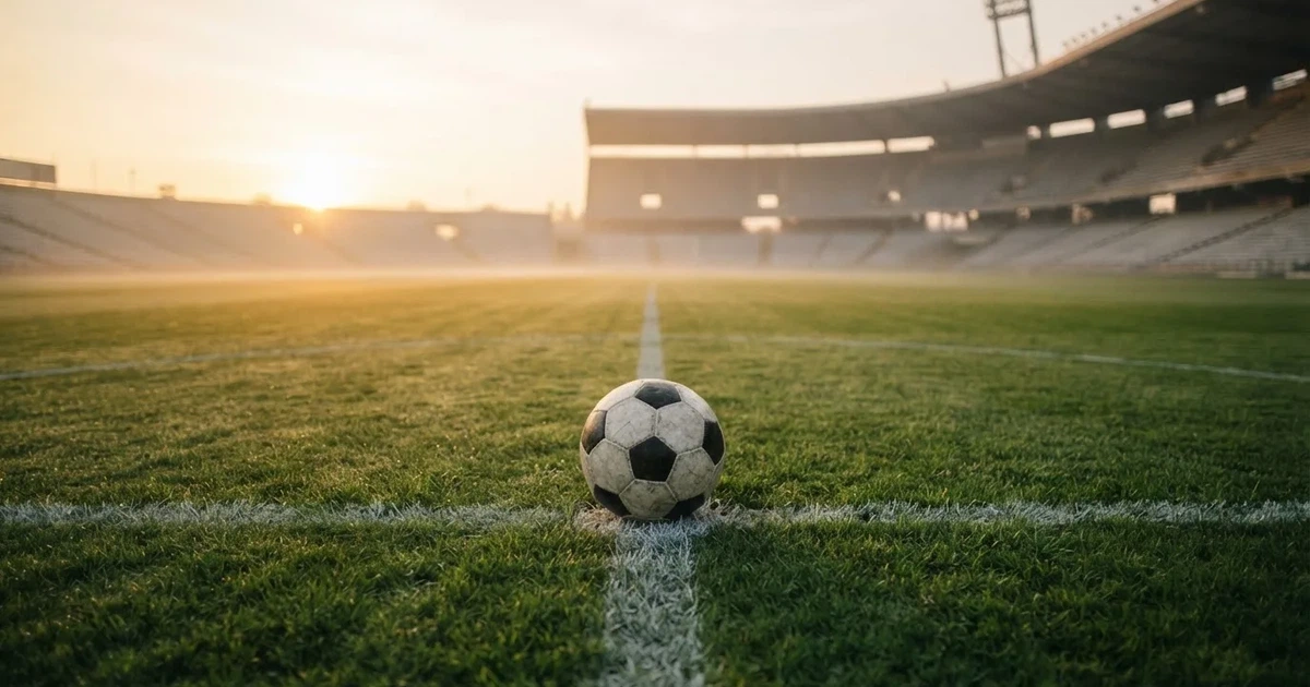 Un balón en el punto central de un campo de césped a la luz de la mañana