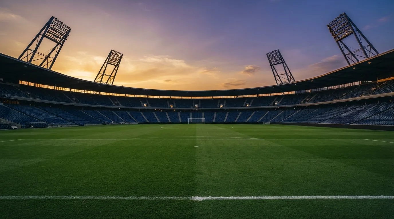 Un estadio de fútbol vacío con torres de iluminación al atardecer