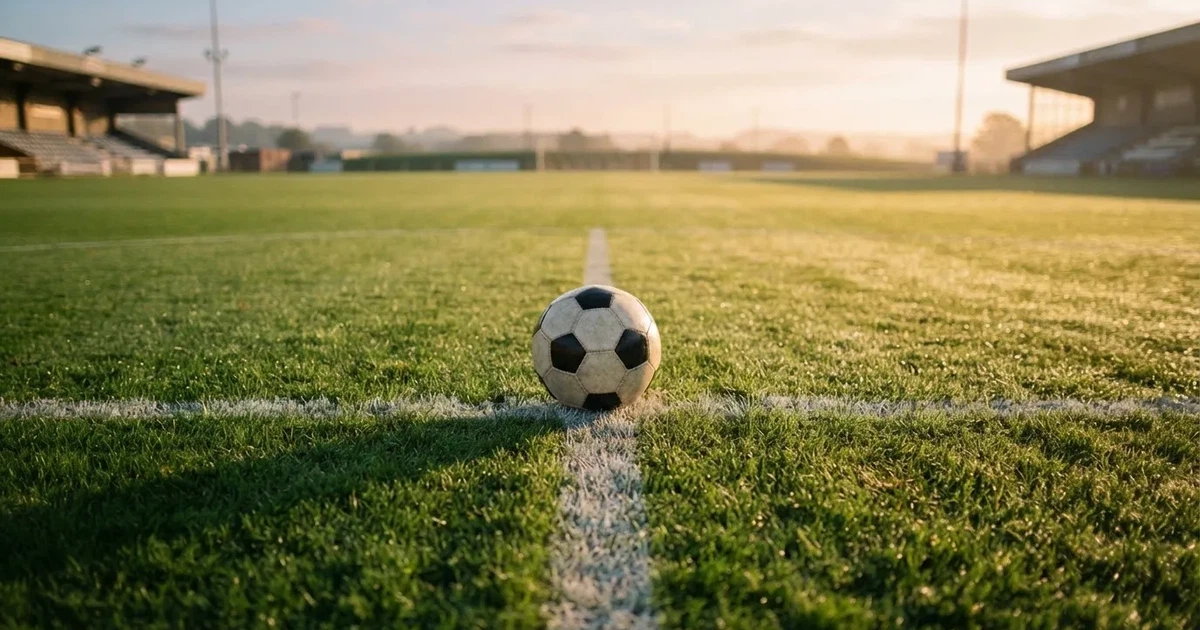 Un balón en el punto central de un campo de césped a la luz de la mañana