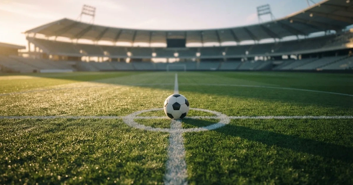 Un balón en el punto central de un campo de césped a la luz de la mañana