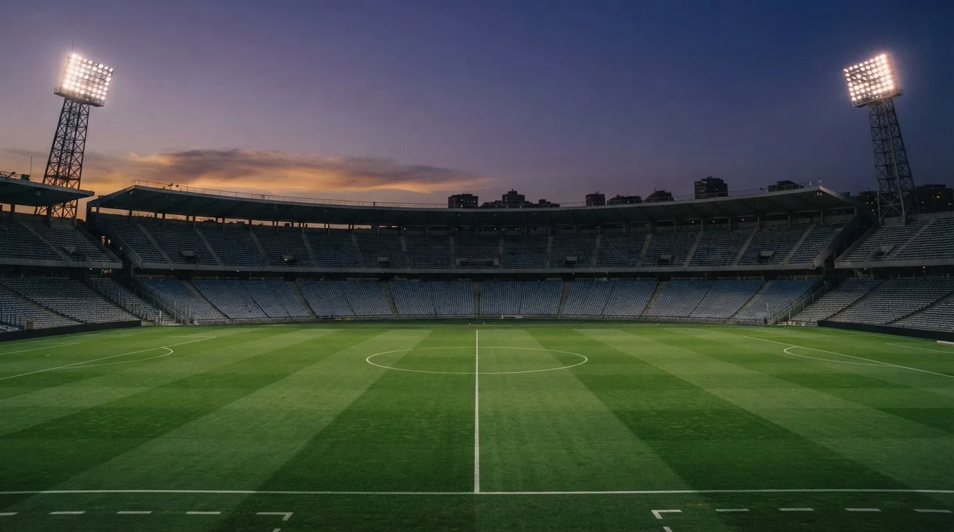 Un estadio de fútbol vacío con torres de iluminación al atardecer