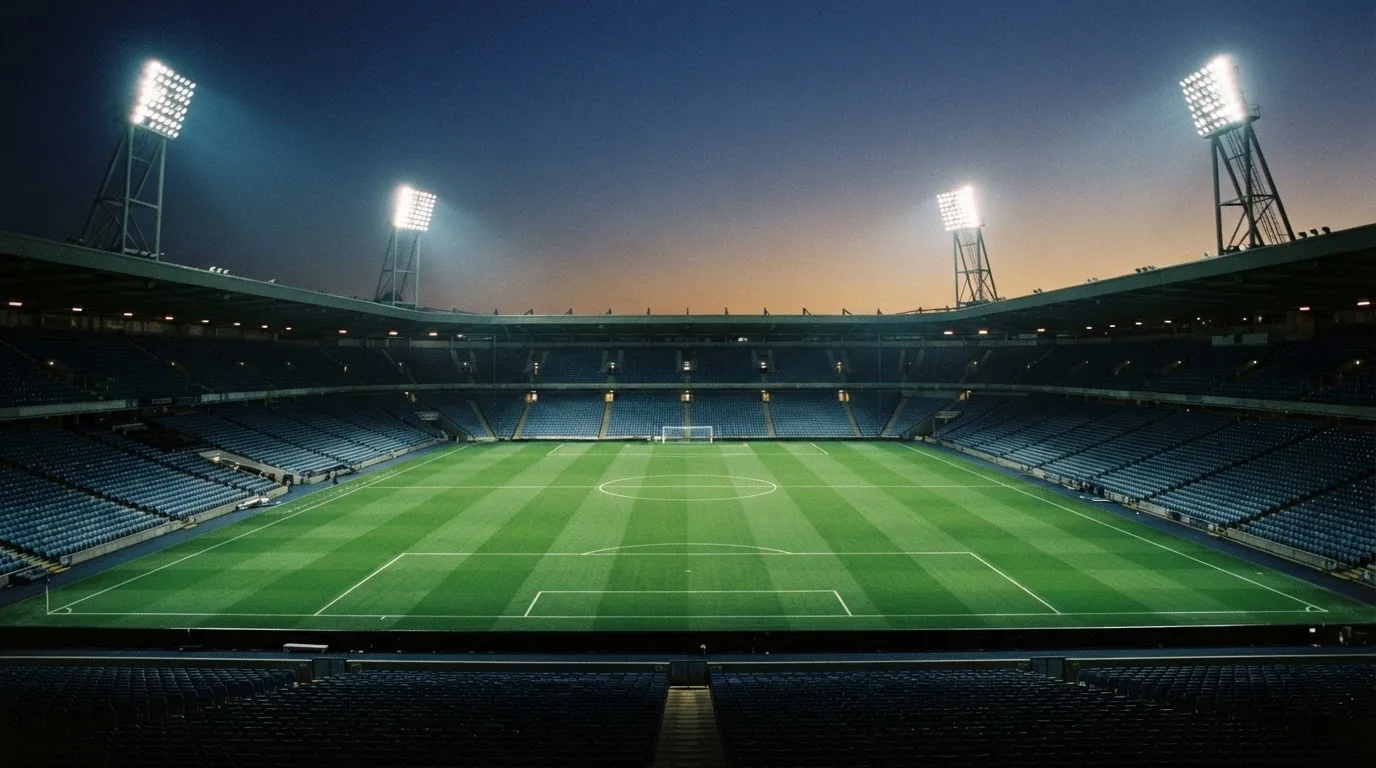 Un estadio de fútbol vacío con torres de iluminación al atardecer