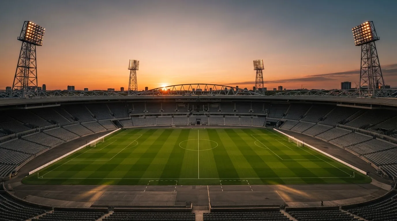 Un estadio de fútbol vacío con torres de iluminación al atardecer