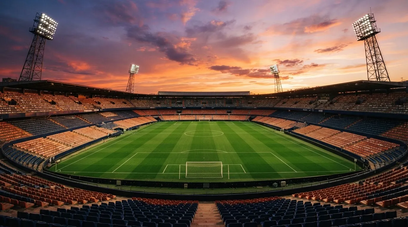 Un estadio de fútbol vacío con torres de iluminación al atardecer